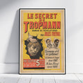 A framed vintage French book cover poster for 'Le Secret de Tropmann' by Jules Freval, leaning against a white wall on a light wooden floor.