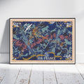 A framed vintage-style poster titled 'AIR FRANCE' leaning against a white wall on a white wooden floor. The poster features a dark blue background with illustrated airplanes, birds, stars, and ornate gold and teal decorative elements.